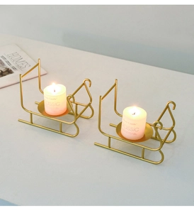 Close-up of golden sleigh candle holders with white candles on a minimalist desk