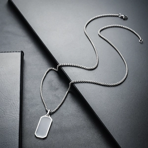 Detail shot of a silver box chain with a blank rectangular tag pendant in stainless steel