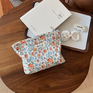 Close-up of floral print cosmetic bag with lace hair accessories on a wooden tray