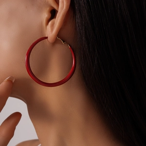 Gros plan d'une grande créole rouge brillante en résine portée par un mannequin