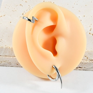 Detailed view of silver lightning bolt clip and spiked ring earring on silicone ear model