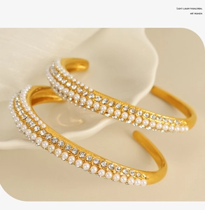 Detailed close-up of a gold-plated open cuff bracelet with double pearl and zircon rows