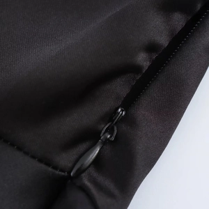 Detail eines versteckten Reißverschlusses an einem schwarzen Satin-Midikleid mit Webstruktur