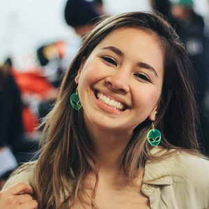 Vibrant fluorescent green acrylic alien drop earrings worn by a smiling female model