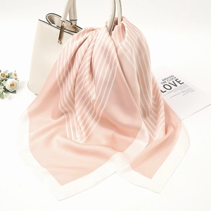 Detail of elegant paisley print silk scarf draped over a luxury handbag for styling