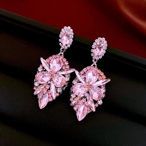Macro shot of pink crystal drop earrings with silver flower details on black texture