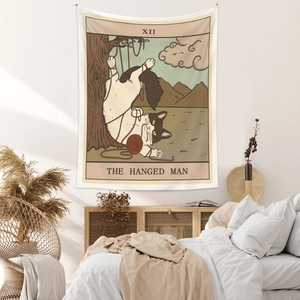 Detailed view of tarot style tapestry featuring a cat as The Hanged Man in a cozy bedroom
