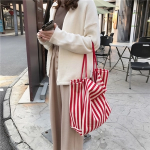 Outdoor street style view of a red and white striped large canvas tote bag being worn