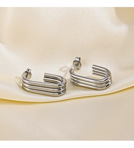 Detail of silver triple-layered C-shape earrings on elegant silk fabric background