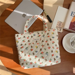 Quilted cotton tote bag with bear pattern and floral print on a warm wooden desk