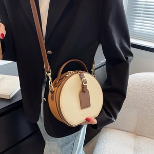 Retro color-block round crossbody bag in beige and brown leather shown on a black blazer