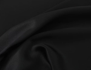 Macro detail of high-quality black lace fabric showing silky texture and elegant drape