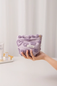 Detail of purple plush cosmetic bag with heart-shaped zipper and soft texture