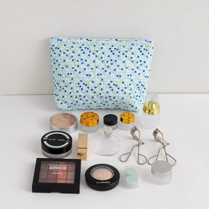 Quilted cosmetic bag with blue checkered pattern and colorful dots shown with makeup items