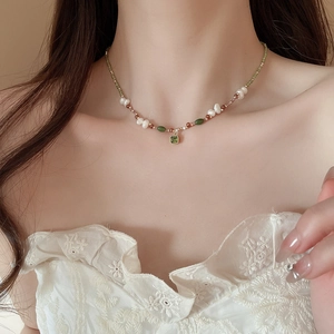 Macro shot of 18k gold plated necklace with freshwater pearls and green zircon pendant