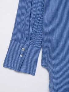 Détail du poignet d'une chemise à rayures bleues avec boutons en nacre et tissu lin-coton