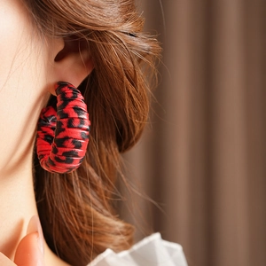 Close-up of leopard print leather C-shape hoop earrings on model with retro style