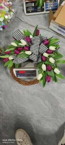 Close-up of white and purple tulip wreath with black checkered bow on a weighing scale