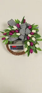 Close-up of white and purple tulip wreath with black checkered bow on a weighing scale