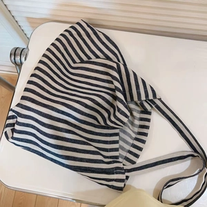 Minimalist striped canvas tote bag with wide straps on a white chair in a casual setting
