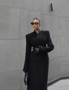 Détail d'un manteau long noir élégant avec taille cintrée et texture premium minimaliste