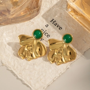 Detail of vintage gold earrings with green natural stone on artistic petal background