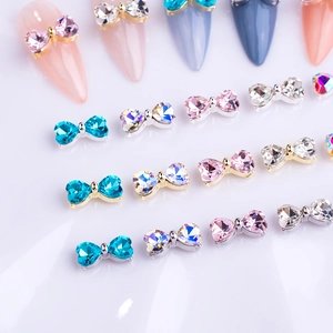 Detail shot of colorful bow-shaped nail art charms with crystals in gold and silver bases