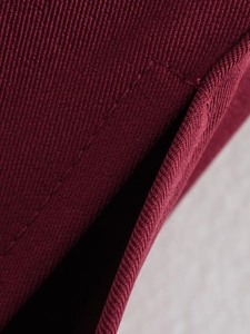 Gros plan détaillé du tissu en sergé rouge foncé montrant la texture et les coutures