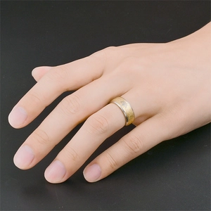 Dettaglio di anello in acciaio inox con finitura oro satinato e incisione sulla mano.