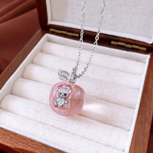 Detailed shot of apple pendant with zircon bear on velvet lining inside jewelry box