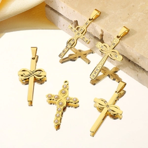 Détail de pendentifs croix plaqués or 18k avec strass sur une surface miroir