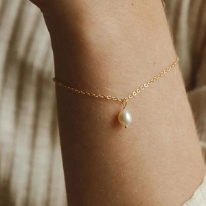 Detailaufnahme eines 14K vergoldeten Titanarmbands mit einer weißen Tropfenperle