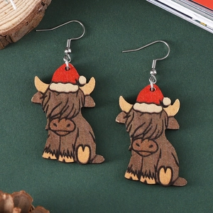 Christmas highland cow wooden earrings with red hats on dark green pine cone backdrop