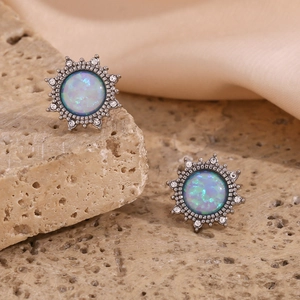 Detail of sunburst earring with blue opal center and pavé zircon on silk fabric