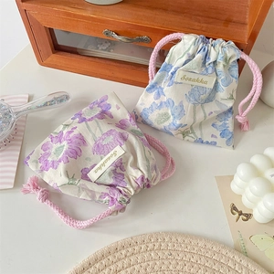 Dettaglio di sacchetti a coulisse floreali viola e blu con cordini intrecciati rosa