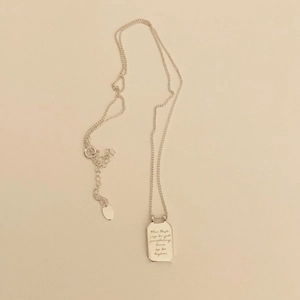 Sterling silver rectangle pendant necklace with handwritten engraving on beige background
