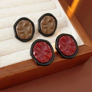 Detail view of geometric irregular stud earrings in black with brown and red resin centers