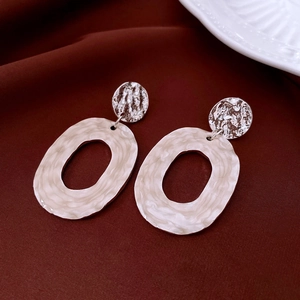 Detail view of silver geometric earrings with textured metal finish on red velvet fabric