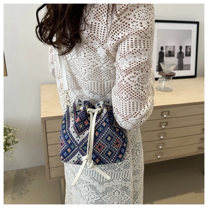 Detail of blue geometric woven bucket bag with orange patterns and drawstring closure
