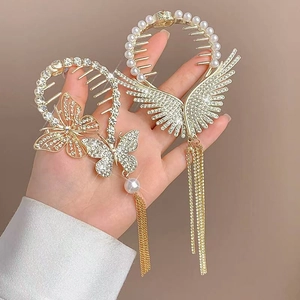 Dettaglio di eleganti fermagli per capelli dorati con strass, perle e lunghe nappe