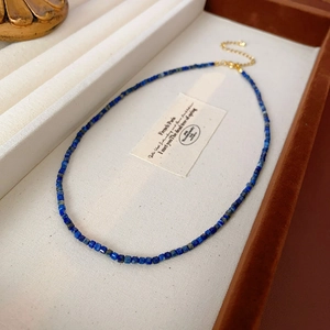 Détail d'un collier en perles carrées de lapis-lazuli bleu avec chaîne dorée