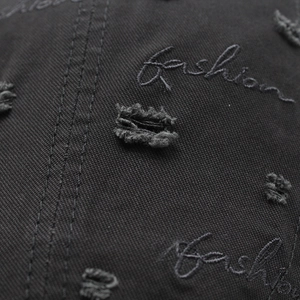 Close-up of black cotton twill beret featuring distressed details and fashion embroidery