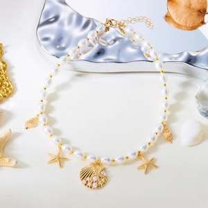 Detail of shell and starfish charms on a white pearl necklace with golden accents