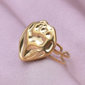 Macro shot of gold-plated heart ring with hammered texture on soft pink silk fabric