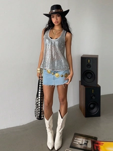Zilveren pailletten topje gecombineerd met denim rok en accessoires in modieuze setting