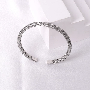 Detailed view of silver braided stainless steel cuff bracelet on white silk texture