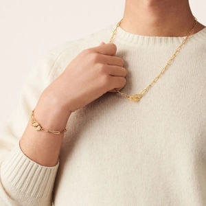 Detailed view of 18k gold handcuff pendant necklace and bracelet set on a model