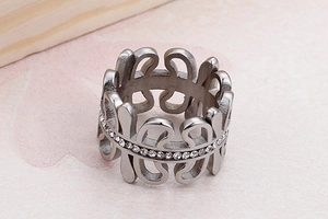Detail of silver hollow wide band ring with inlaid white zircon on pink stone background