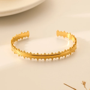 Detailed view of gold stainless steel cuff bracelet with scalloped crown edges