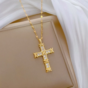 Elegant gold titanium steel cross necklace with brilliant zircons on a jewelry box